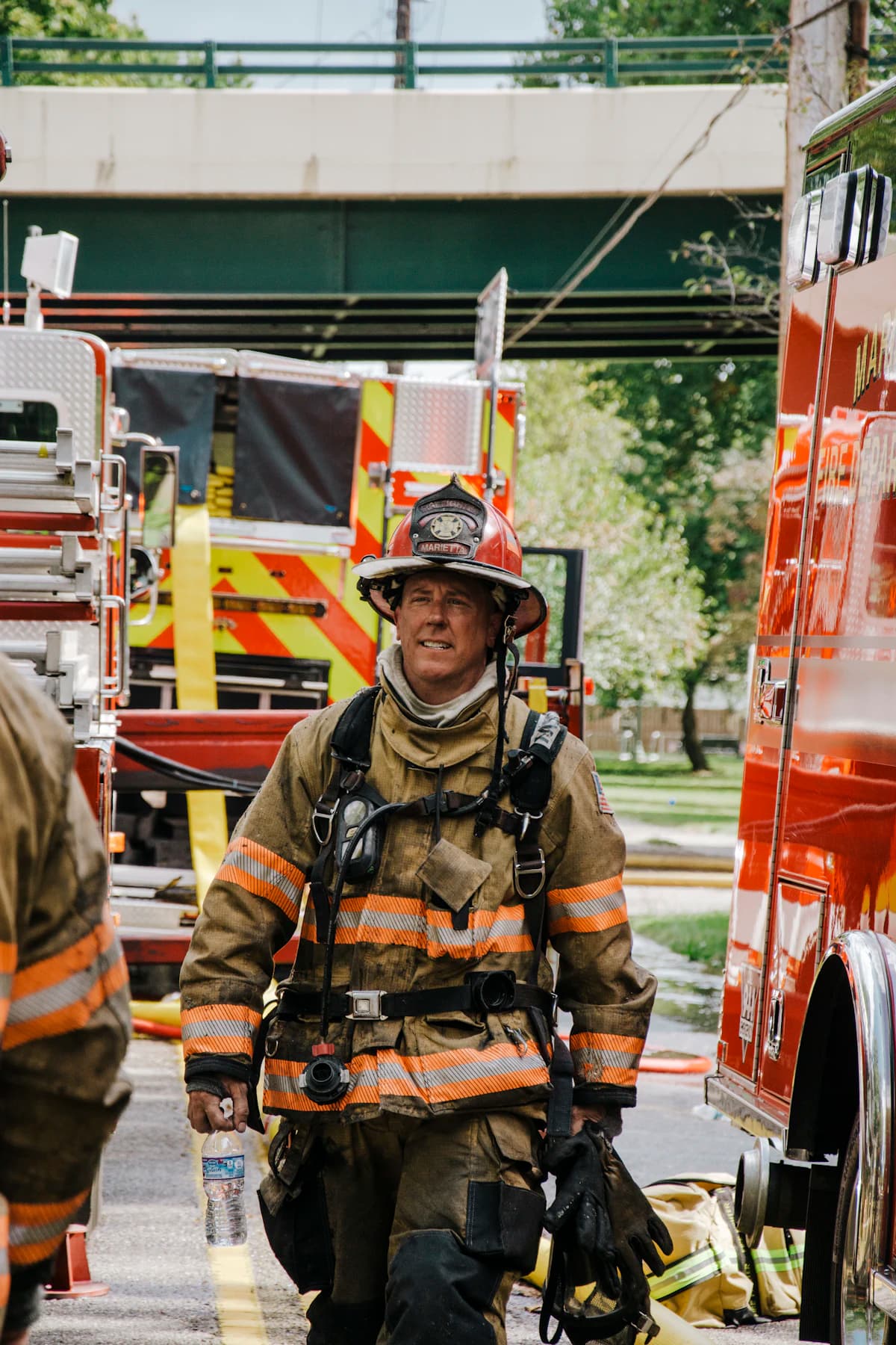 A firefighter walking between two engines after a call